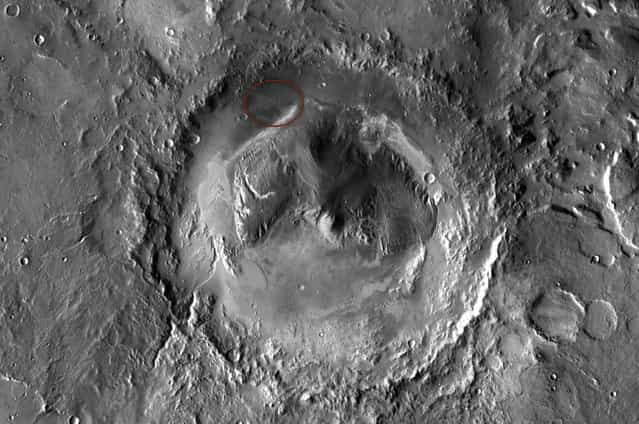 NASA has selected Gale crater as the landing site for the Mars Science Laboratory mission. The missions rover will be placed on the ground in a northern portion of the crater in August 2012. This view of Gale is a mosaic of observations made in the visible-light portion of the spectrum by the Thermal Emission Imaging System camera on NASAs Mars Odyssey orbiter. Gale crater is 96 miles (154 kilometers) in diameter and holds a layered mountain rising about 3 miles (5 kilometers) above the crater floor. The ellipse superimposed on this image indicates the intended landing area, 12.4 miles (20 kilometers) by 15.5 miles (25 kilometers). The portion of the crater within the landing area has an alluvial fan likely formed by water-carried sediments. The lower layers of the nearby mountain – within driving distance for Curiosity – contain minerals indicating a wet history. (Photo by NASA/JPL-Caltech/ASU)