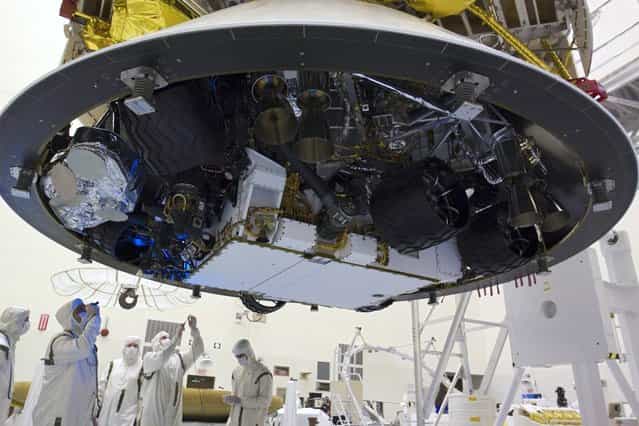 In the Payload Hazardous Servicing Facility at NASAs Kennedy Space Center in Florida, technicians inspect beneath NASAs Mars Science Laboratory (MSL) mission aeroshell, (containing the rover Curiosity), which has been mated to the cruise stage. (Photo by Glenn Benson/NASA)