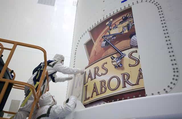 The Mars Science Laboratory (MSL) mission logo begins to take shape as technicians install it on the exterior of an Atlas V rockets payload fairing inside the Payload Hazardous Processing Facility in Florida, on October 29, 2011. (Photo by Jim Grossmann/NASA)