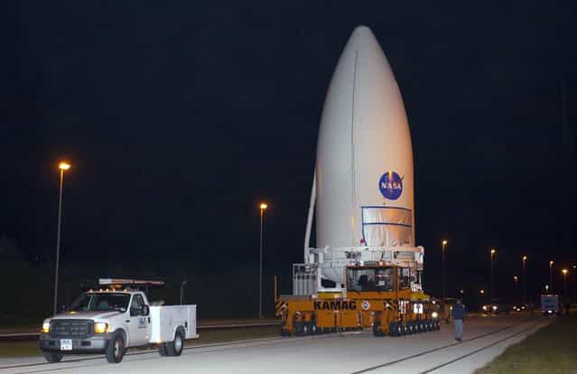 Standing atop a payload transporter on November 3, 2011, the Atlas V payload fairing containing NASAs Mars Science Laboratory spacecraft rolls down a darkened roadway during the early morning move from Kennedy Space Centers Payload Hazardous Servicing Facility to Space Launch Complex 41. (Photo by Kim Shiflett/NASA)