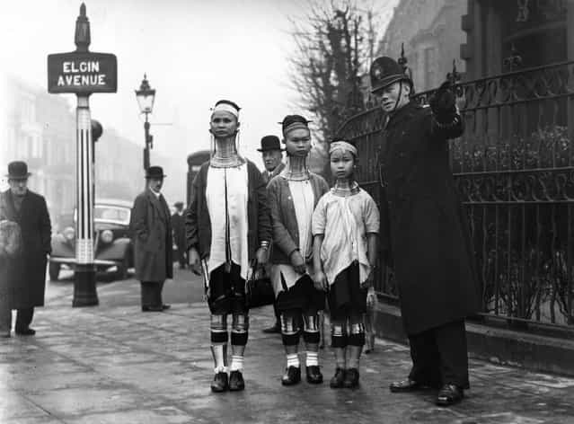 A policeman in London directing three giraffe necked women from Burma along Elgin Avenue, London, 1935. (Photo by General Photographic Agency)