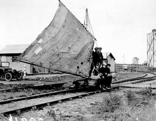 A group of men travelling along a railway track using a sail-driven wagon at Spurn Head, England, October 1922.