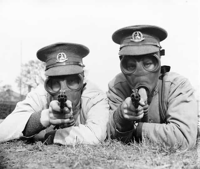 Soldiers of the Royal Norfolk Regiment at Aldershot, Hampshire getting used to revolver shooting while wearing a gas mask. UK, 28th March 1936. (Photo by Reg Speller/Fox Photos)