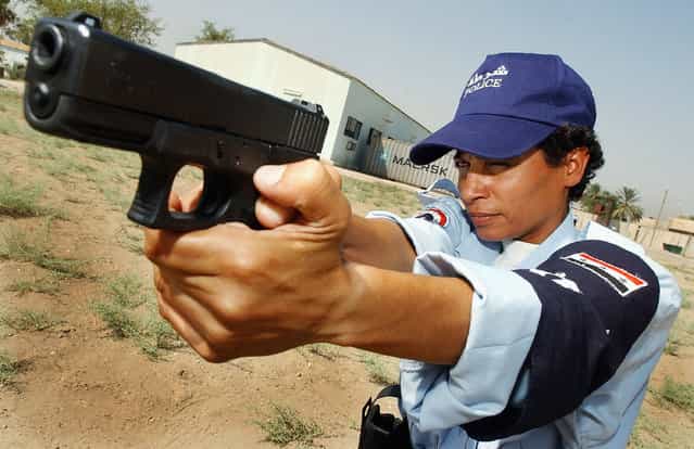 Female police recruit Aziza Ali, 30, aims her Glock 9mm pistol at a target on the gunnery range at the law enforcement academy July 18, 2004 in Baghdad, Iraq. (Photo by Wathiq Khuzaie)