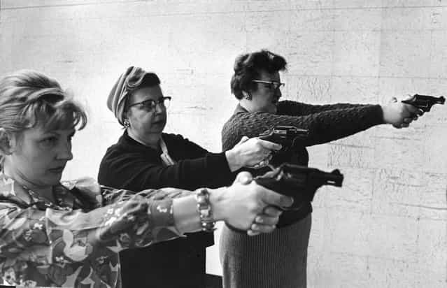 Two middle-aged women and one younger woman aim revolvers at a target in a indoor shooting range in Dearborn, Michigan, 1967 or 1968. (Photo by London Daily Express)