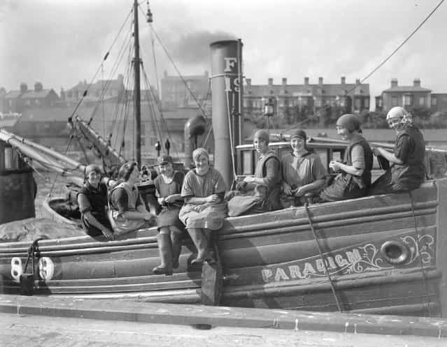 A group of Scottish fisherwomen arrive at Great Yarmouth aboard the fishing vessel [Paradigm] for the autumn herring season. The women busy themselves knitting while waiting for the boats to bring in the herring. 27th September 1928. (Photo by Harold Clements/London Express)