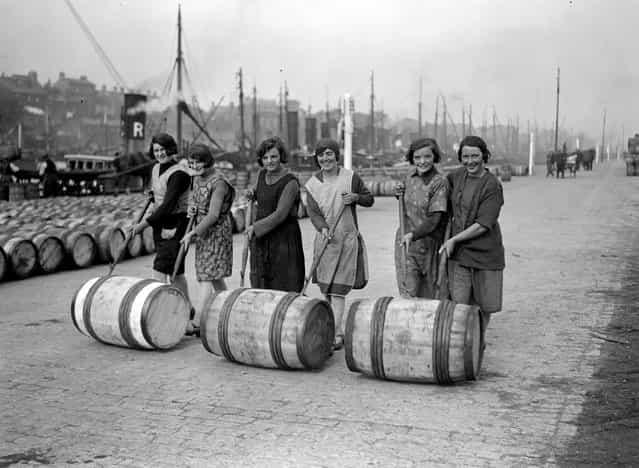 Yarmouth fisher-girls pushing barrels of herring along the quayside using long poles, 1929. (Photo by Fox Photos)