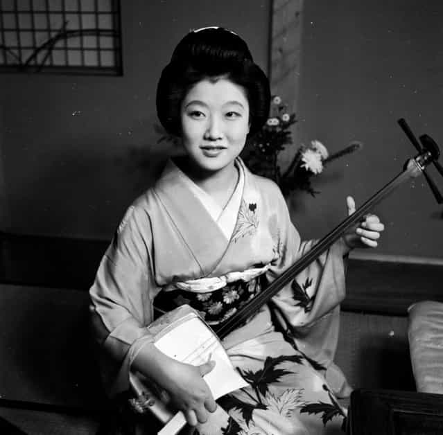 A Japanese Geisha wearing a kimono and sitting with her Samisen, a traditional string instrument, circa 1950. (Photo by Evans/Three Lions)