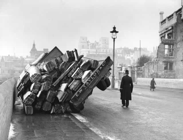 A lorry loaded with timber, overturned in icy conditions in Queen Victoria Street, London, 1955. (Photo by L. Blandford)