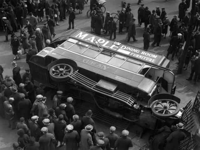 A crowd of passers-by gather round an overturned bus in Shirland Road, London, circa 1925. (Photo by Topical Press Agency)