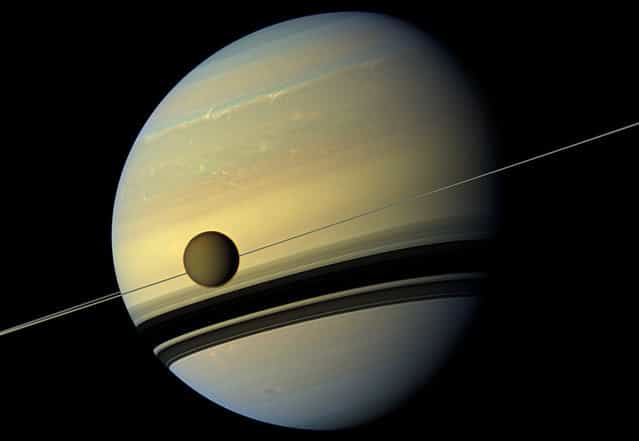 A giant of a moon appears before a giant of a planet undergoing seasonal changes in this natural color view of Titan and Saturn from NASA's Cassini spacecraft, on May 6, 2012. As the seasons have changed in the Saturnian system, and spring has come to the north and autumn to the south, the azure blue in the northern Saturnian hemisphere that greeted Cassini upon its arrival in 2004 is now fading. The southern hemisphere, in its approach to winter, is taking on a bluish hue. This change is likely due to the reduced intensity of ultraviolet light and the haze it produces in the hemisphere approaching winter, and the increasing intensity of ultraviolet light and haze production in the hemisphere approaching summer. (Photo by NASA/JPL-Caltech/SSI)