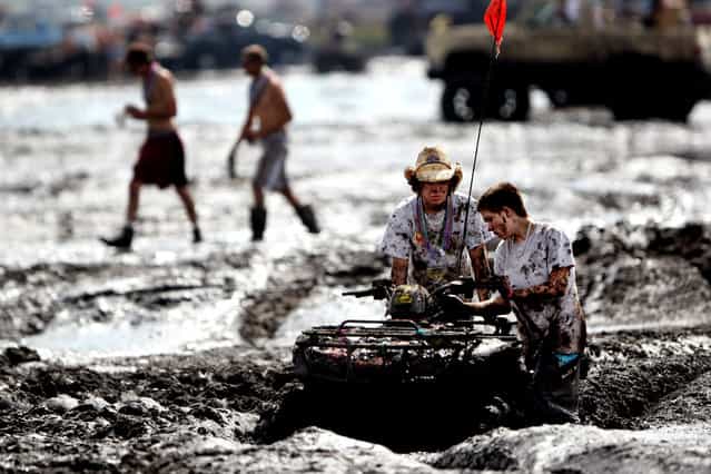 An ATV gets trapped in the mud bog. Many people underestimate the depth of the mud and get stuck. (Photo by Gary Coronado/The Palm Beach Post)