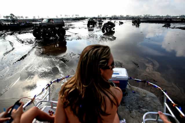 Jessica Reynolds of West Palm Beach sits atop the swamp buggy [Killing a Little Time] as it cruises through the mud bog. (Photo by Gary Coronado/The Palm Beach Post)