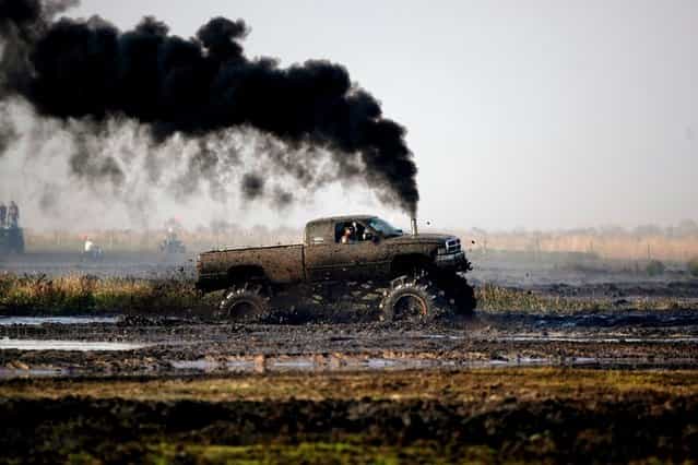 A diesel powered truck billows smoke as it rumbles through the mud bog