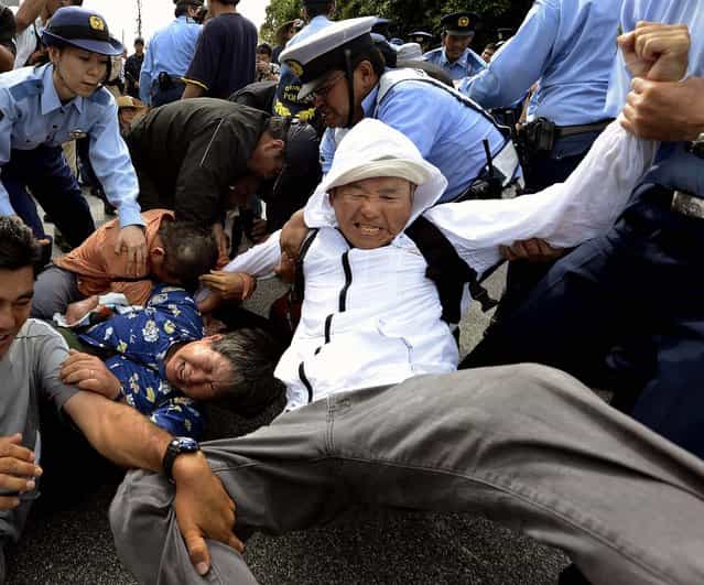 Police officers try to remove demonstrators who staged a sit-in against the planned deployment of Osprey aircraft, in front of a gate at Marine Corps Air Station Futenma in Ginowan City, Okinawa, Japan, on September 27, 2012. (Photo by Kyodo)