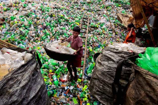 A Bangladeshi child laborer carries empty bottles at a plastic bottle recycling center in Dhaka, Bangladesh, on September 18, 2012. (Photo by A.M. Ahad/Associated Press)