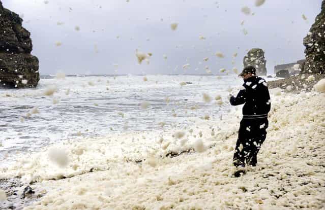 Aron Martin braves the high winds and rain on Marsden Beach , England, on September 24, 2012. Much of the country is being battered by high winds and heavy rain. (Photo by Owen Humphreys/Associated Press)