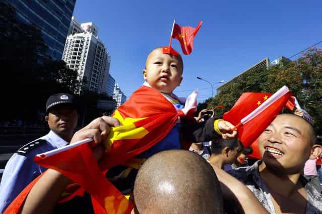 A child draped in a Chinese national flag sits on a man's shoulders during an anti-Japan protest near the Japanese Embassy in Beijing, on September 18, 2012. The 81st anniversary of a Japanese invasion brought a fresh wave of anti-Japan demonstrations in China, with thousands of protesters venting anger over the colonial past and a current dispute involving contested islands in the East China Sea. (Photo by Ng Han Guan/Associated Press)