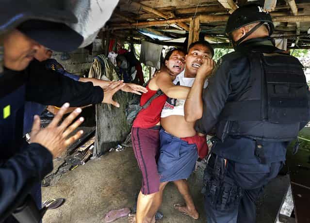 Philippine National Police try to arrest resisting settlers during the demolition of their shanty in Taguig City, on September 20, 2012. The informal settlers' community of mostly retired police and military personnel was demolished to pave the way for new development projects. (Photo by Bullit Marquez/Associated Press)