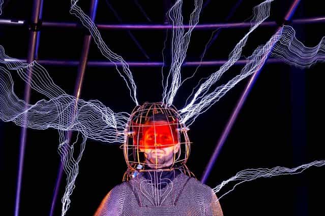Blaine stands inside the apparatus, surrounded by a million volts of electric currents streamed by tesla coils. The stunt, sponsored by Intel, is the latest of daredevil endeavors by the magician whose previous stunts included being encased in ice for over 60 hours in Times Square, on October 5, 2012. (Photo by John Minchillo/Associated Press)