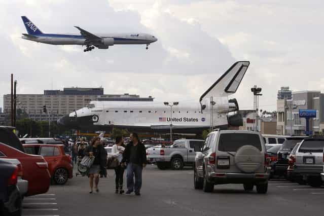 A jet lands at Los Angeles International Airport (LAX) behind the space shuttle Endeavour during a break in its movement as it is transported from LAX to the California Science Center in Exposition Park where it will be on permanent public display on October 12, 2012 in Los Angeles, California. Endeavour was flown cross-country atop NASA's Shuttle Carrier Aircraft from Kennedy Space Center in Florida to LAX on its last flight ever on September 21. Completed in 1991, Endeavour was built to replace the space shuttle Challenger which disintegrated during a catastrophic re-entry accident. This fifth and final space shuttle orbiter circled the earth 4,671 times and traveled nearly 123 million miles during its 25 missions from 1992 to 2011. (Photo by David McNew)