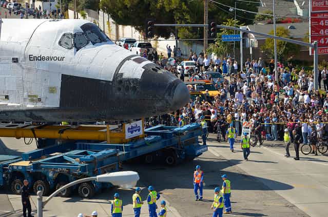 The Space Shuttle Endeavour is moved slowly along a city street October 12, 2012, in Los Angeles, California. The shuttle is on its last mission – a 12-mile creep through city streets, past an eclectic mix of strip malls, mom-and-pop shops, tidy lawns and faded apartment buildings. Its final destination is the California Science Center in South Los Angeles where it will be put on display. (Photo by Mark J. Terrill-Pool)