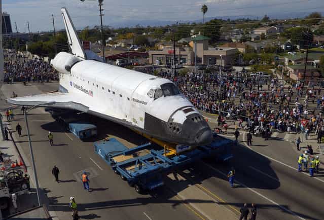 The Space Shuttle Endeavour is moved slowly along a city street October 12, 2012, in Los Angeles, California. The shuttle is on its last mission – a 12-mile creep through city streets, past an eclectic mix of strip malls, mom-and-pop shops, tidy lawns and faded apartment buildings. Its final destination is the California Science Center in South Los Angeles where it will be put on display. (Photo by Mark J. Terrill-Pool)