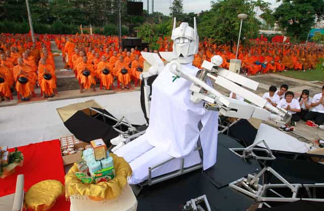 A robot sits before Buddhist monks, as they pray during a mass alms-offering ceremony at King Mongkut's Institute of Technology Ladkrabang in Bangkok, on June 19, 2012. The ceremony was held to mark the 2,600th anniversary of the enlightenment of Lord Buddha. (Photo by Sukree Sukplang/Reuters)