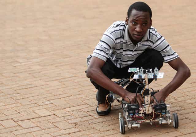 Alvin Kabwama, one of the designers of a prototype robot that can detect and disarm Improvised Explosive Devices attempts to switch it on at Makerere University's College of Engineering, Design Art and Telecommunication in Kampala, Uganda, on June 6, 2012. The robot is remotely controlled by a computer and can navigate a flat surface of up to a 20m radius. The development comes in the wake of continuous terrorist threats as a result of the country's contribution of forces to the African Union peace keeping mission in Somalia. (Photo by Edward Echwalu/Reuters)