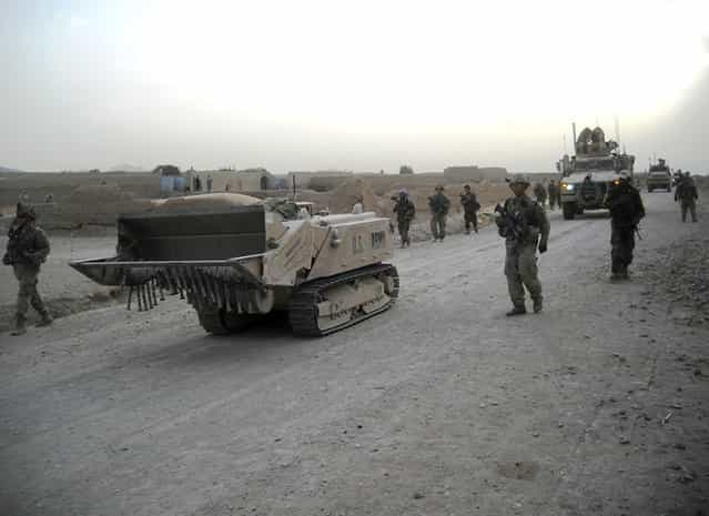 Soldiers with 3rd Brigade, 10th Mountain Division, travel alongside a Doking mine-clearance vehicle in Zharay District, Kandahar province, Afghanistan, during a recent patrol. The Doking is a remote-controlled, unmanned robotic vehicle, used for mine and route clearance. (Photo by U.S. Army)