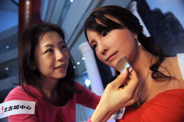 Akie Koh, a stylist from Japan, makes final preparations on the face of Geminoid F, a female robot, in Hong Kong, on March 28, 2012. The Geminoid F robot, developed by Ishiguro Laboratory in Osaka University and ATR Intelligent Robotics and Communication Laboratories, will be on display with other robots at City Plaza's [Robots in Motion 2012] exhibition from March 29 to April 15. (Photo by Antony Dickson/AFP Photo)