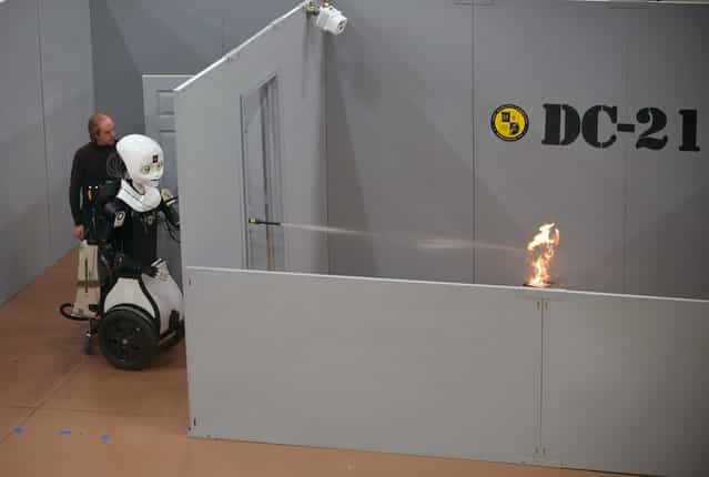 Octavia, a mobile, dexterous, social (MDS) robot, puts out a fire in the prototyping high bay of the just-opened Laboratory for Autonomous Systems Research at the Naval Research Laboratory in Washington, D.C. The LASR facility will integrate science and technology components into research prototype systems and will become the nerve center for basic research that supports autonomous systems research for the Navy and Marine Corps. (Photo by John Williams/U.S. Navy)