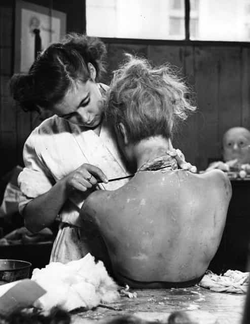 An employee of Gems Ltd, a firm based in a disused chapel off Portobello Road, London, fixes the wax head of a model onto its body. The firm makes wax and composition models, including likenesses of criminals, politicians and royalty, as well as mannequins to display fashion. November 1950. (Photo by John Chillingworth/Picture Post)