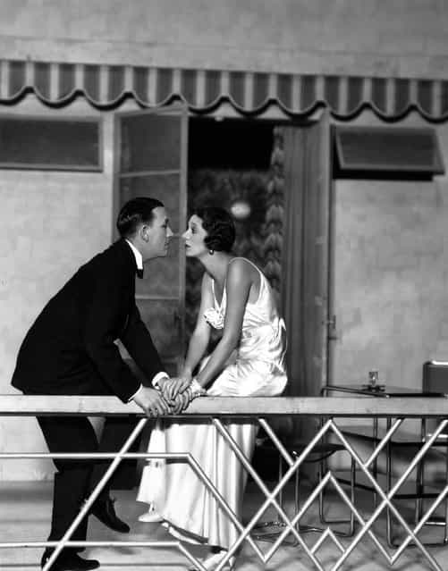 Noel Coward (1899–1973) and Gertrude Lawrence sit on a balcony staring into each other's eyes, in a scene from the play [Private Lives], at the Phoenix Theatre, London, 1930. Costumes by Molyneux. (Photo by Sasha)