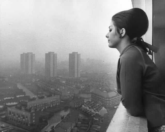 Mrs. Linda Marshall leans over the balcony of her new home on the 19th floor flat of Ferrier Point in Canning Town. She was evacuated from Ronan Point after a section of the block collapsed killing four people. 10th July 1969. (Photo by Jim Gray/Keystone)