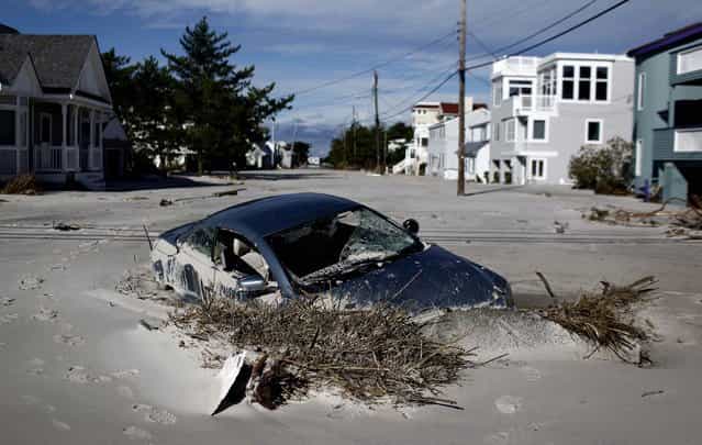 A car is submerged in sand on the south end of Long Beach Island, N.J. in the aftermath of superstorm Sandy, October 31, 2012. (Photo by Luke Sharrett/The New York Times)