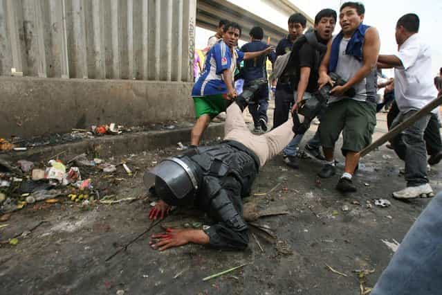 Protesters drag a riot police officer who was knocked off his horse with rocks thrown by workers of 'La Parada' wholesale market in Lima, Peru, on October 25, 2012. Clashes between the wholesale market workers and police officers left two people dead and more than 100 injured. (Photo by Alessandro Currarino/Diario El Comercio/Reuters)