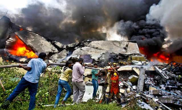 Firemen and volunteers work to extinguish fire in a building housing a paint factory in Bangalore, India, November 8, 2012. (Photo by Aijaz Rahi/Associated Press)