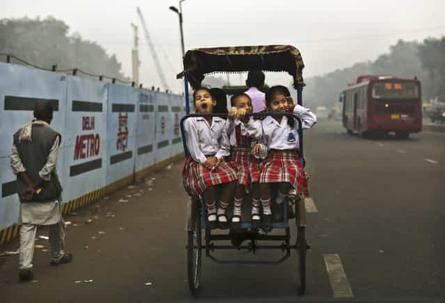 A girl yawns as she rides with friends to school on a bicycle rickshaw in New Delhi, India, October 31, 2012. (Photo by Kevin Frayer/Associated Press)