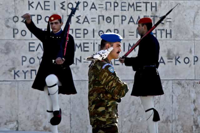A pigeon sits on the shoulder of a Greek Presidential Guard as his colleagues in traditional Evzones' costumes perform ceremonial duties at the tomb of the unknown soldier in Athens, October 31, 2012. (Photo by Kostas Tsironis/Associated Press)