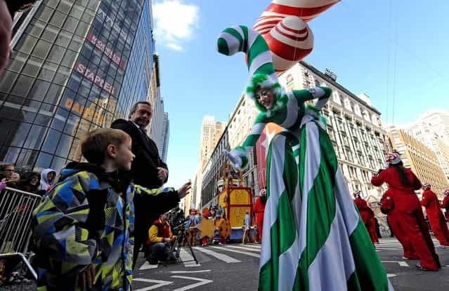 A Candy Cane girl reaches out to a child at Herald Square during the 86th annual Macy's Thanksgiving Day Parade. (Photo by Louis Lanzano/Associated Press)