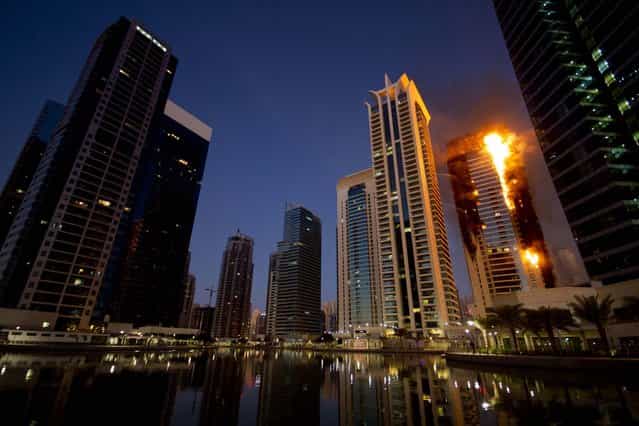 Flames engulf a portion of the Tamweel residential tower at Jumeirah Lakes Towers in Dubai, United Arab Emirates, November 18, 2012. Civil defense officials did not give immediate details on possible casualties or the cause of the predawn fire. (Photo by Kaveh Kashani/Associated Press)