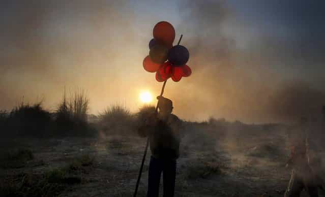 A balloon seller waits for customers on the banks of the Yamuna River during the final day of the Chhath Puja festival in New Delhi, November 20, 2012. The ancient Hindu festival is celebrated to thank the Sun God for sustaining life on earth. (Photo by Altaf Qadri/Associated Press)
