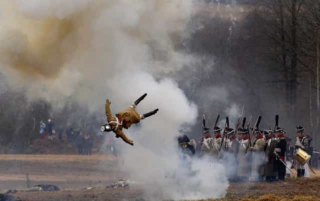 Men dressed as 1812-era Russian and French soldiers re-enact a staged battle as a dummy soldier is blown up, near the Belarus village of Bryli, to mark the 200th anniversary of the Berezina battle during Napoleon's army retreat from Russia, November 24, 2012. The retreat across the Berezina of the remnants of Napoleon's Grand Army, which invaded Russia June 24, 1812, took place from November 26 to 29, 1812. About 50,000 people, soldiers from both sides and civilians, were killed during the crossing. (Photo by Sergei Grits/Associated Press)