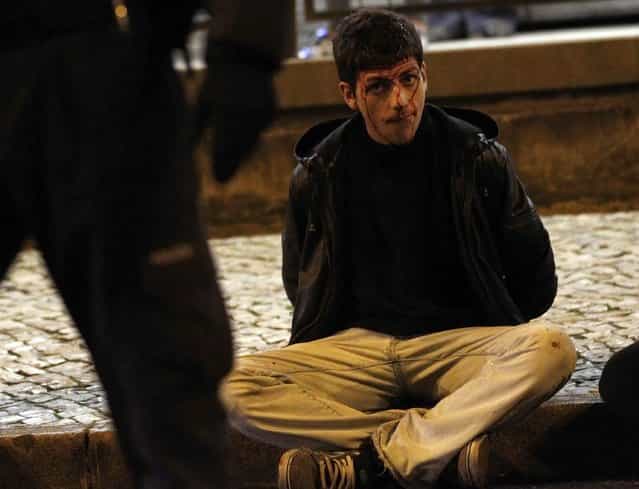 An injured protester sits in the street after being detained during clashes at a 24-hour nationwide general strike in Lisbon, November 14, 2012. Spanish and Portuguese workers will stage the first coordinated general strike across the Iberian Peninsula on Wednesday, shutting transport, grounding flights and closing schools to protest against spending cuts and tax hikes. (Photo by Rafael Marchante/Reuters)