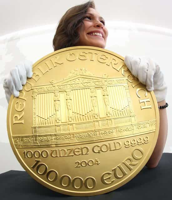 A woman presents Europe's biggest gold coin during an exhibition at the Pro Aurum trade house in Hamburg, northern Germany. The so-called [Big Phil] made after the model of an Austrian coin weighs around 31 kilograms and is worth more than 1.3 million euros or 1.7 million US dollars. [Big Phil] is on display at Pro Aurum until November 17, 2012. (Photo by Christian Charisius)
