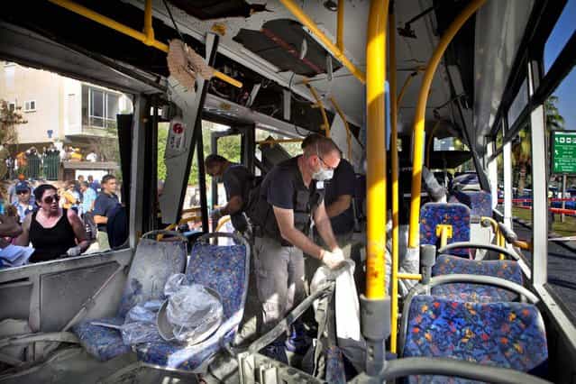 Israeli police officers examine a destroyed bus at the site of a bombing in Tel Aviv, Israel, November 21, 2012. A bomb ripped through an Israeli bus near the nation's military headquarters in Tel Aviv, wounding 16 people. (Photo by Dan Balilty/Associated Press)