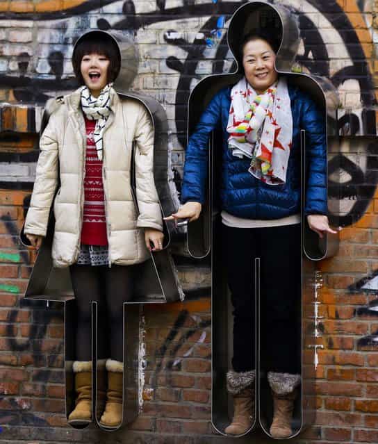 Women pose in body shaped metal frames titled [You and Me] by artist Zhang Zhaohui at the 798 Art District in Beijing, November 21, 2012. (Photo by Lee Jin-man/Associated Press)