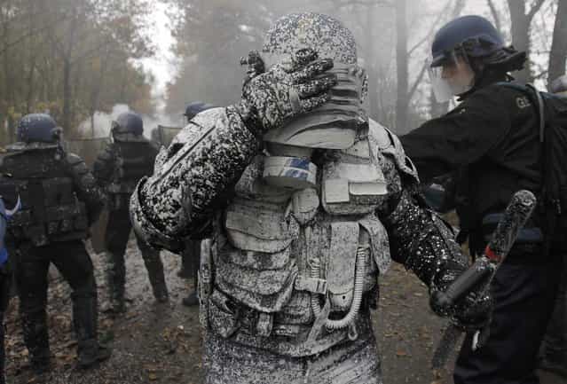 A French riot gendarme reacts after being covered with lime during clashes with demonstrators during an evacuation operation on land that will become the new airport in Notre-Dame-des-Landes, western France November 23, 2012. The new airport, some 30km (19 miles) from Nantes, is scheduled to be constructed for 2017. (Photo by Stephane Mahe/Reuters)