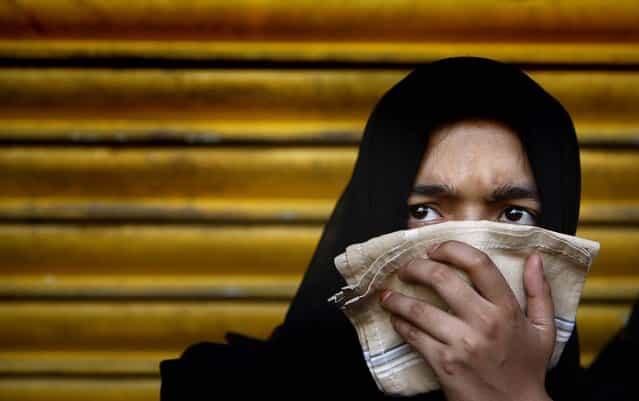 A woman watches a Muharram procession marking Ashura in New Delhi, India, November 25, 2012. (Photo by Tsering Topgyal/Associated Press)
